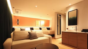 A modern hotel room with a sofa, a small round table, a kitchen area with a sink, and a large mirror. - New Blanc Central Myeongdong (Seoul)
