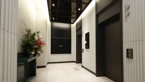 A modern hallway with a patterned floor, a reception desk with a vase of flowers, and an elevator. - New Blanc Central Myeongdong (Seoul)