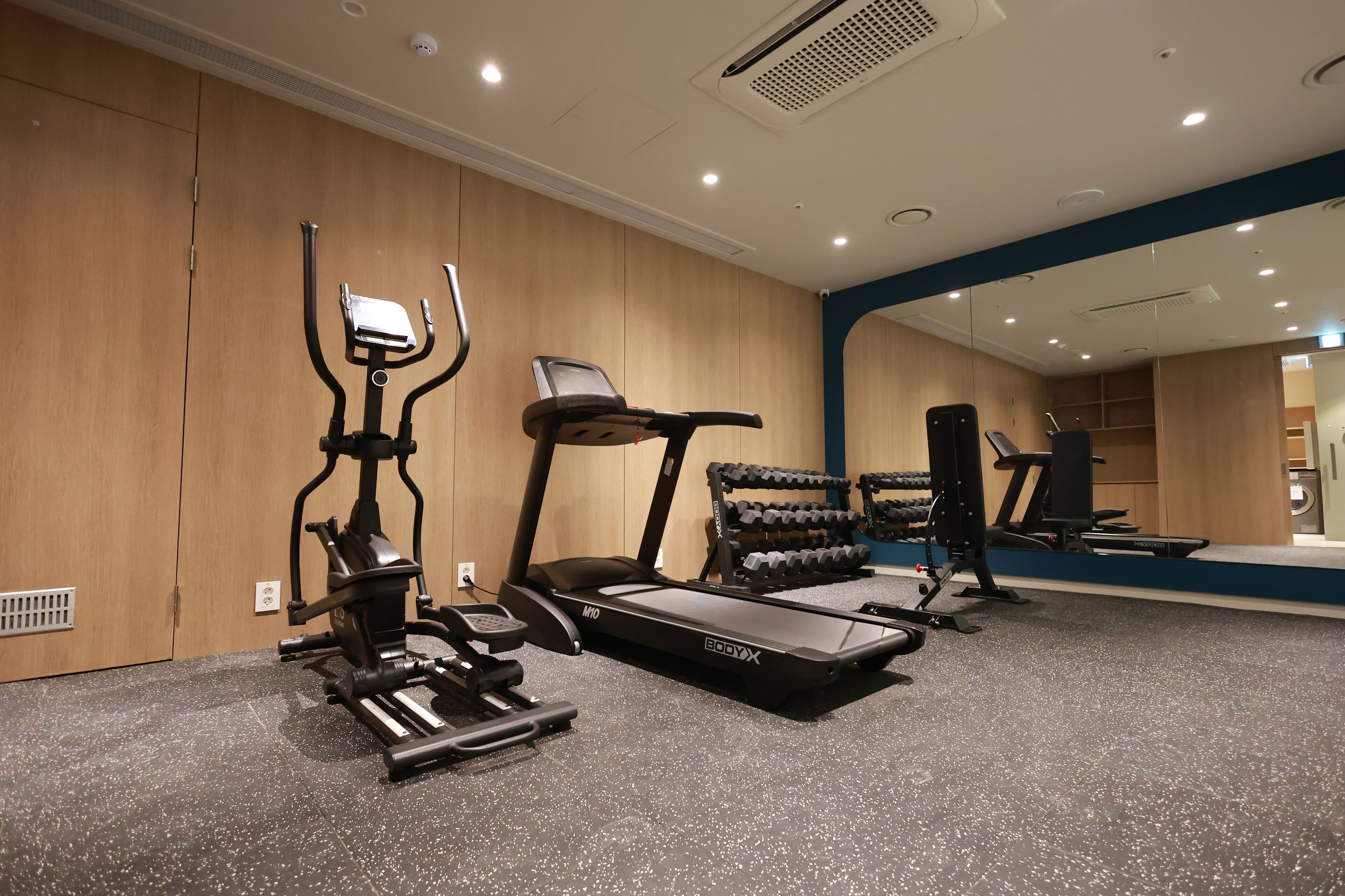 Ein Fitnessstudio mit Laufbändern, Crosstrainern und Gewichtsbänken.