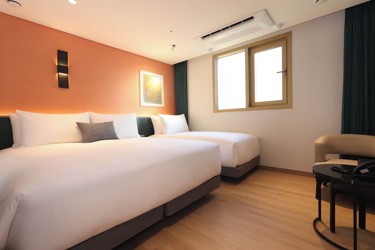 A hotel room with two beds, a desk, and a chair.