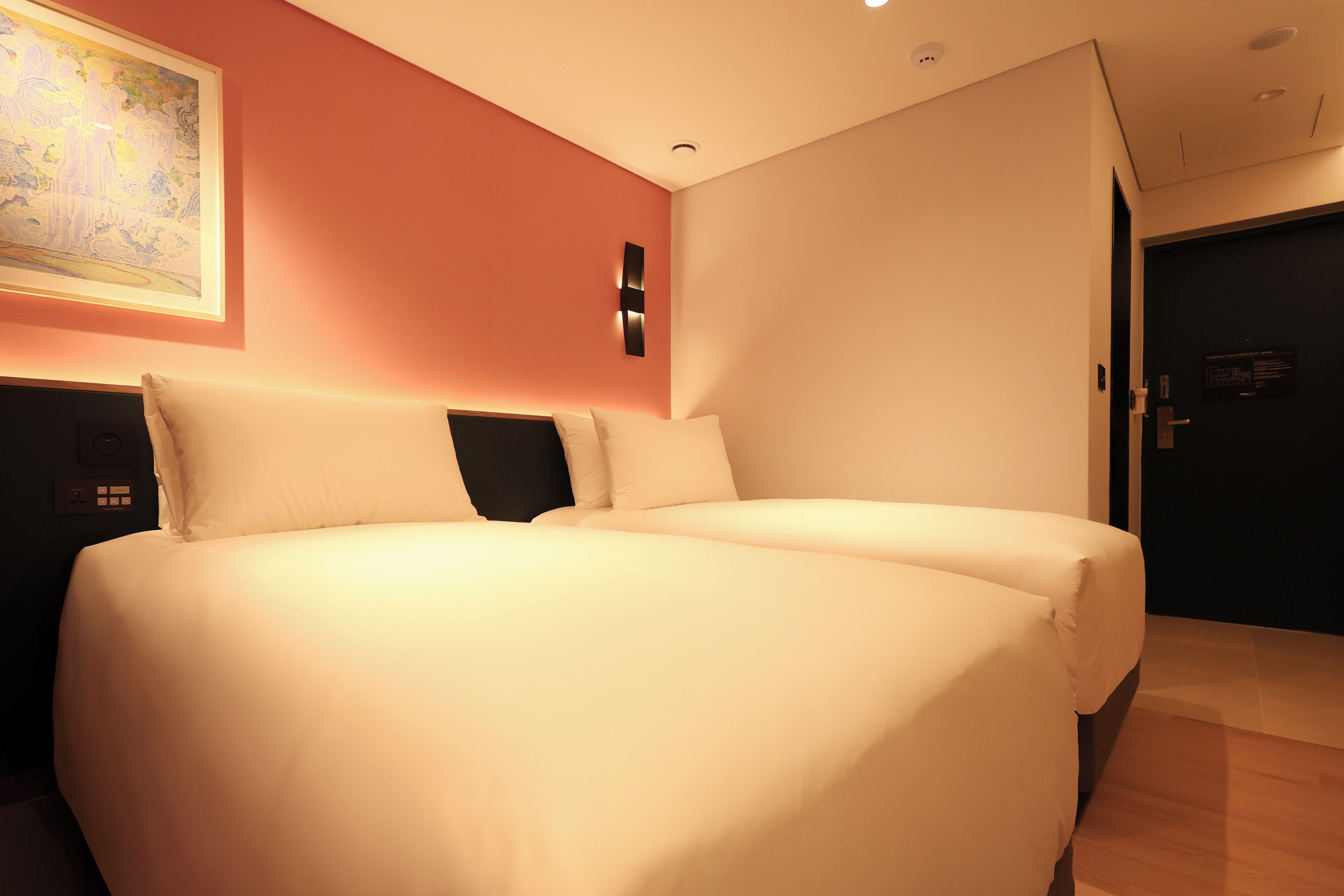 Una habitación de hotel con una cama grande, un cuadro en la pared y una puerta con un letrero.