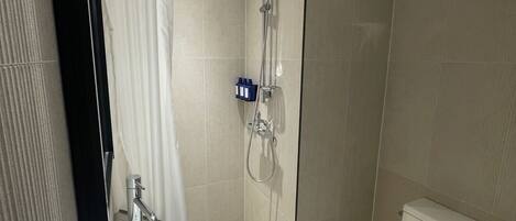 Un baño moderno con lavamanos, inodoro y zona de ducha blancos.