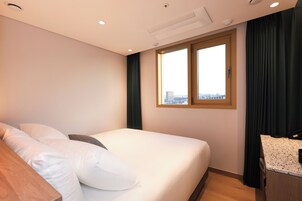 Una habitación de hotel con cama, escritorio y ventana con cortinas.