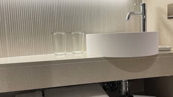 A modern bathroom with a large mirror, a white sink, and a towel rack.