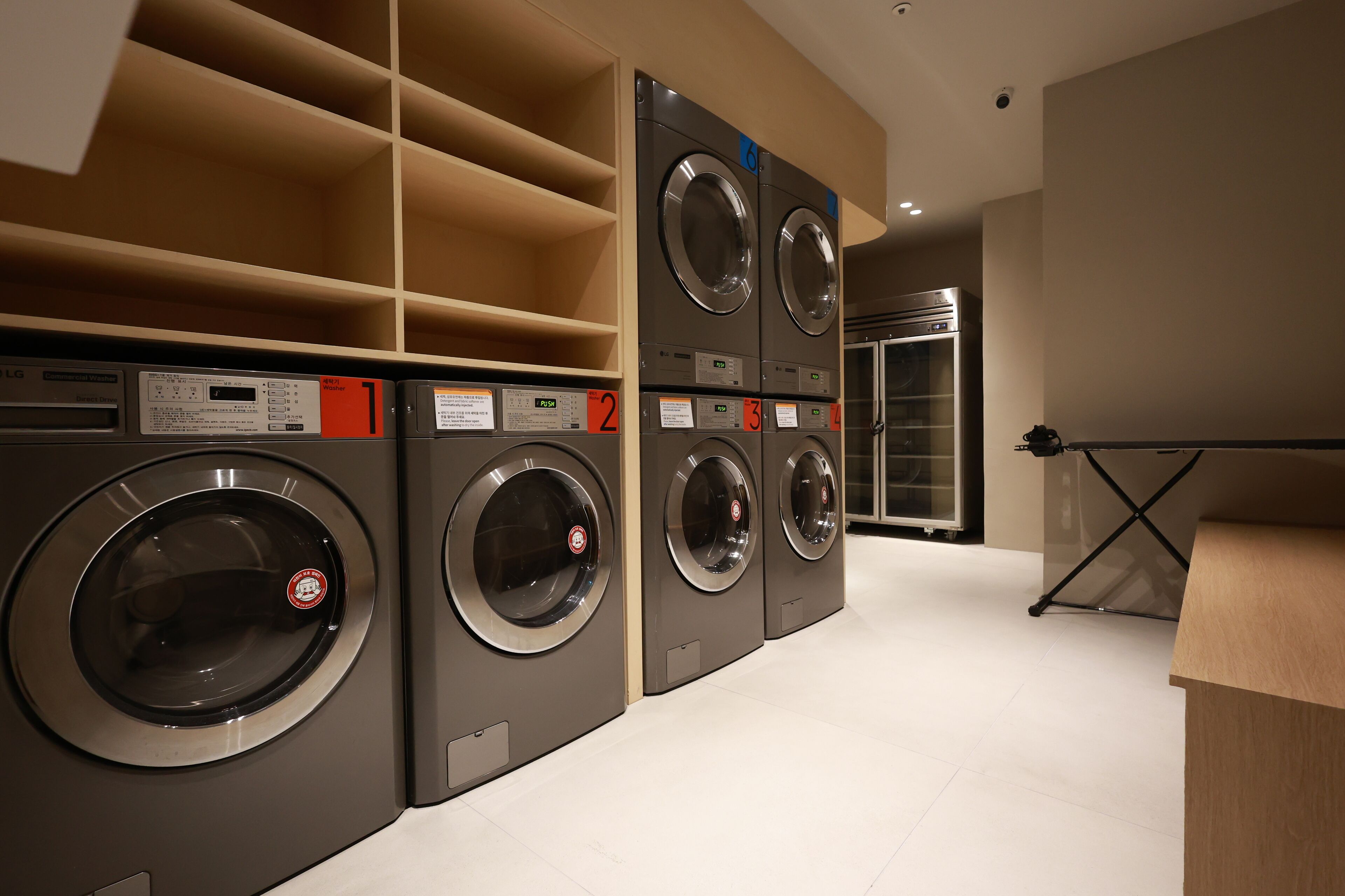 A laundry facility with multiple washing machines, numbered from 1 to 6, and a folding station.