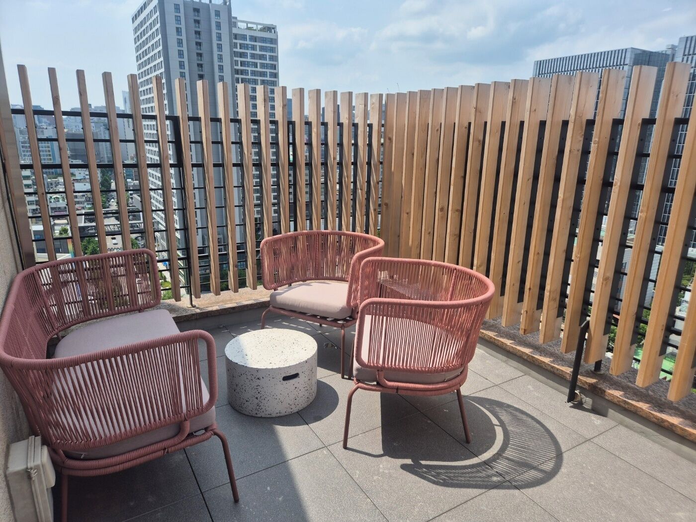 Une terrasse sur le toit, aménagée avec des meubles en osier et une table ronde, le tout entouré d’une clôture en bois.