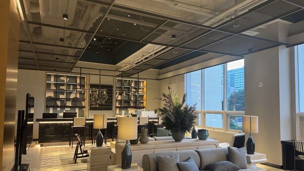 A modern lounge area with a sofa, armchairs, a coffee table, and a large potted plant. There is a bar area with a counter and shelves in the background. - New Blanc Central Myeongdong (Seoul)
