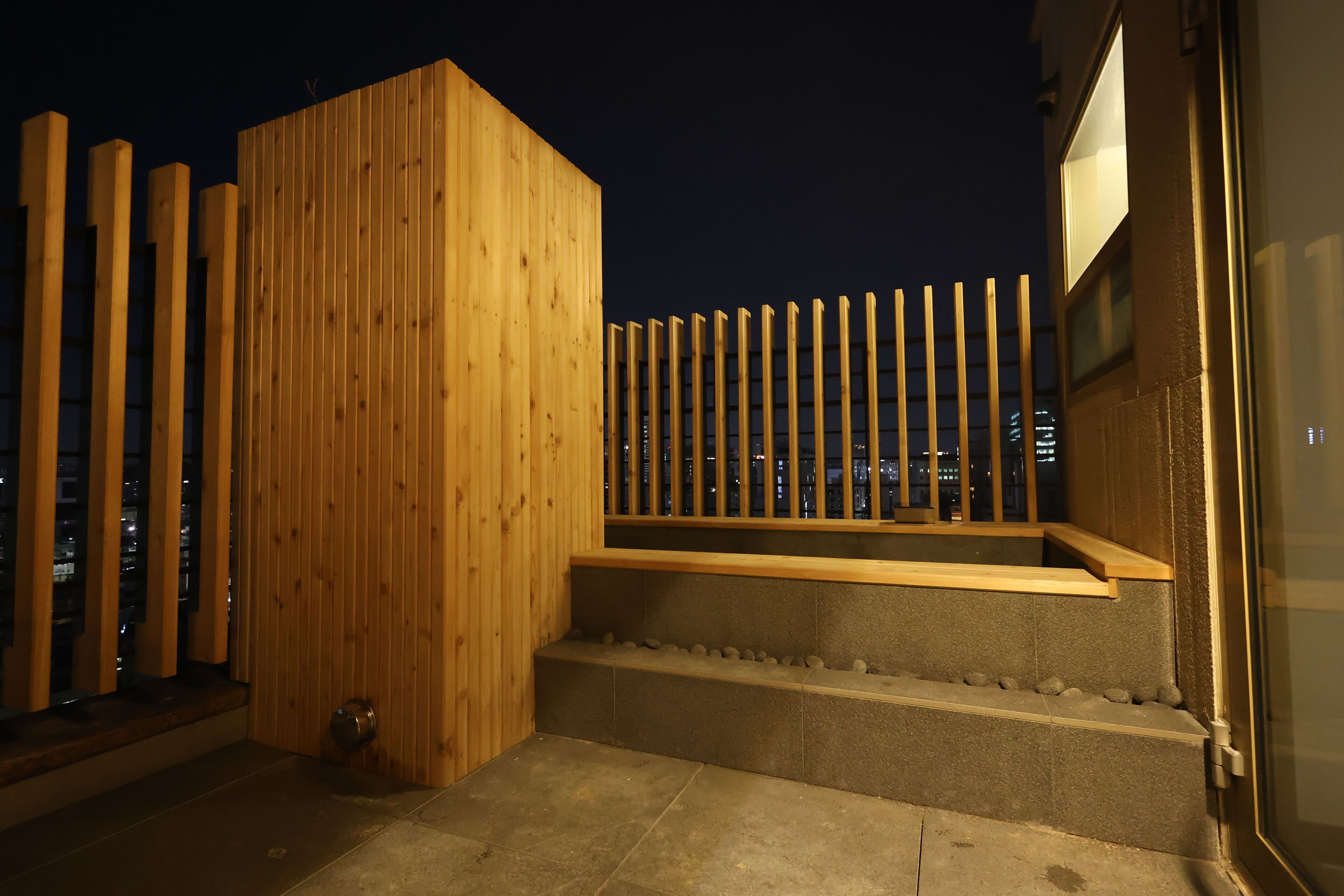 Una estructura de madera con un banco y un escalón pequeño que lleva a un balcón.
