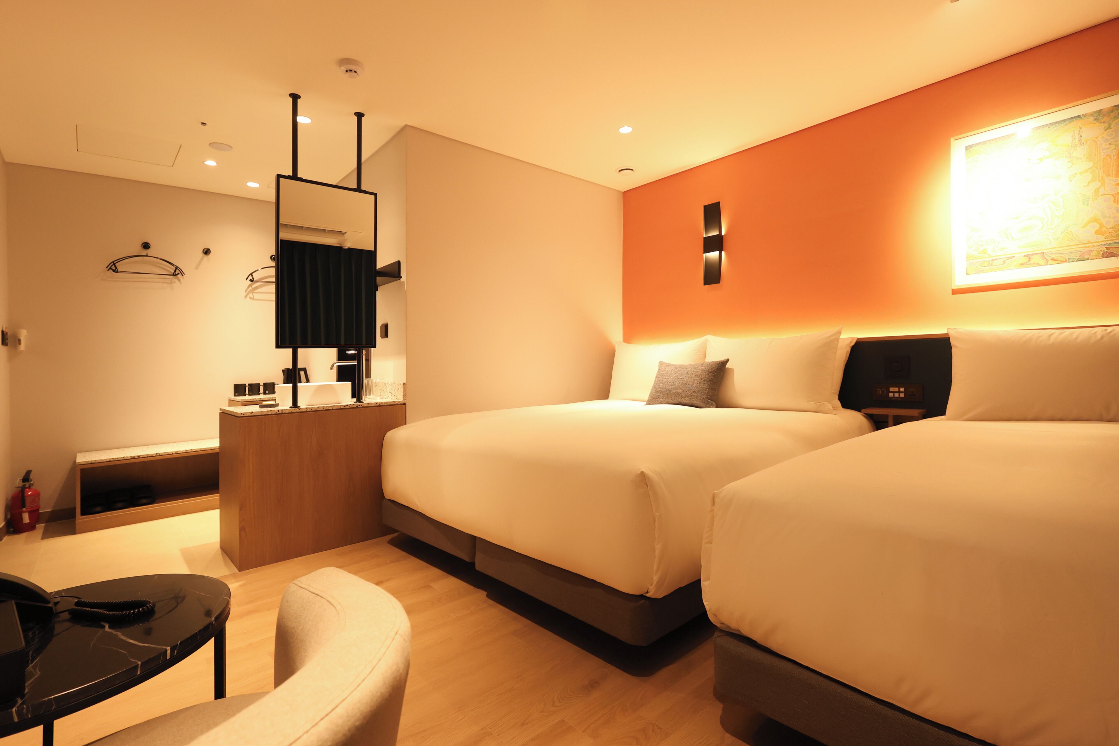 Ein modernes Hotelzimmer mit zwei Betten, einem Schreibtisch und einem Stuhl.