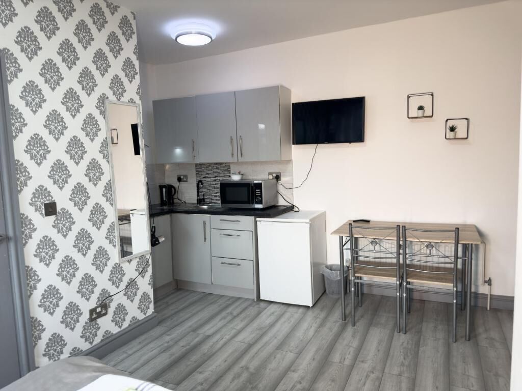Une cuisine compacte avec des meubles blancs, un four à micro-ondes et une petite table à manger avec des chaises.