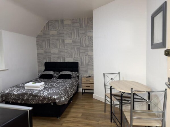 A bedroom with a bed, a desk, and a chair. - Hill's View Apartments (Manchester)