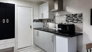 A modern kitchen with white cabinets, a black countertop, and a microwave. - Hill's View Apartments (Manchester)