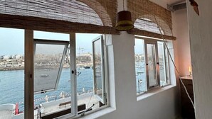 A room with large windows overlooking a body of water, a bed, and a hanging lamp. - Ocean Pearl 2 bedroom (Wied il-Għajn)