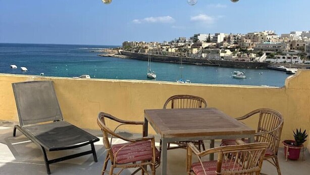 A terrace with a table and chairs, overlooking a coastal town and the sea. - Ocean Pearl 2 bedroom (Wied il-Għajn)
