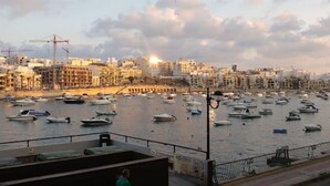 A marina with numerous boats docked, a cityscape with buildings and construction cranes in the background, and a clear sky. - Ocean Pearl 2 bedroom (Wied il-Għajn)