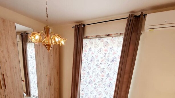 Ein Schlafzimmer mit einem großen Bett, einem Holzschrank, einem Spiegel und einem floralen Vorhang.