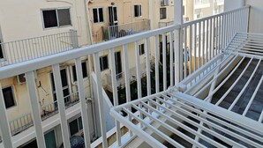 Ein mehrstöckiges Wohngebäude mit Balkonen und weißen Geländern vor blauem Himmel.