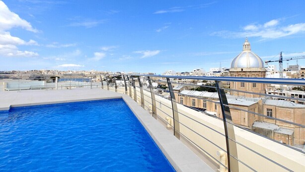 Une piscine sur le toit offrant une vue dégagée sur un bâtiment historique, avec un dôme visible en arrière-plan.