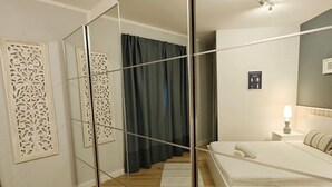 Une chambre à coucher comprenant un lit, un miroir, une table de chevet et un luminaire fixé au mur.