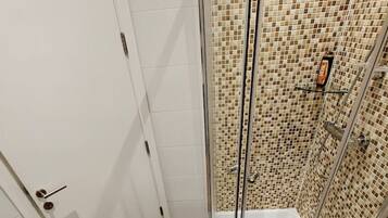 Ein Badezimmer mit Dusche, zwei Waschbecken und Toilette.