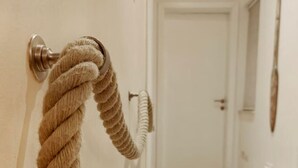 Un couloir avec un tapis à motifs, une porte et une poignée en forme de corde fixée au mur.