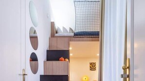 A modern staircase with a wooden finish and a netted upper landing. - TurnKey | Angelo Roma Two Level Cozy Studio (Praha 2)