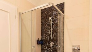 A modern bathroom with a glass-enclosed shower, a white toilet, and a tiled floor. - TurnKey | Wenceslas square Loft Apartment V (Praha 1)