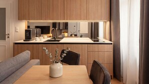 A modern kitchen with wooden cabinets, a built-in oven, and a dining area with a table and chairs. - TurnKey | Wenceslas square Loft Apartment V (Praha 1)