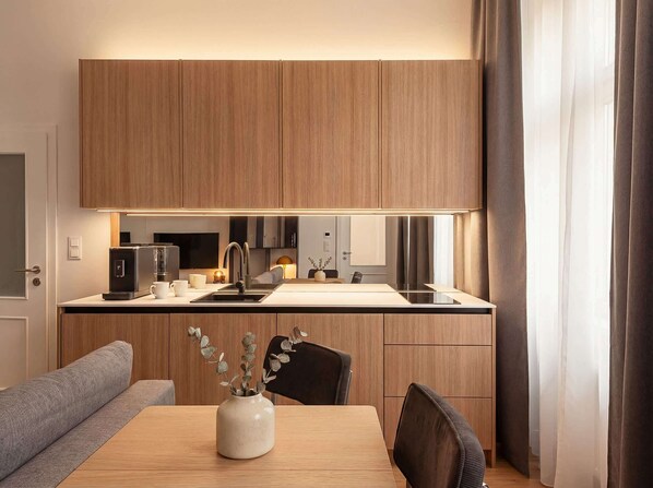 A modern kitchen with wooden cabinets, a built-in oven, and a dining area with a table and chairs.