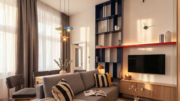 A modern living room with a grey sofa, a coffee table, and a bookshelf.