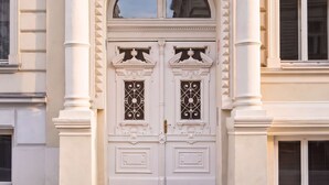 A double door with intricate ironwork, flanked by columns, and a balcony above.