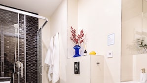 A modern bathroom with a glass shower enclosure, a white toilet, a sink, and a towel rack.