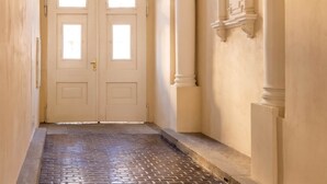 A hallway with a double door, a chandelier, and classical architectural details.
