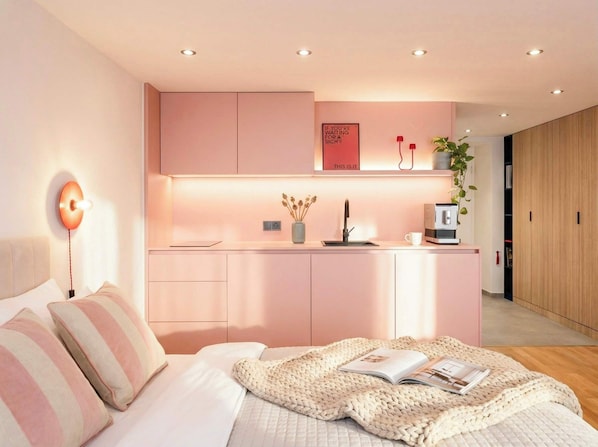 A modern bedroom with a bed, bedside table, and a small kitchenette area. - TurnKey | Wenceslas square Two Level Apartment VI (Praha 1)