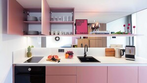 Eine moderne Küche mit rosa Schränken, einer weißen Arbeitsplatte und diversen Küchengeräten.
