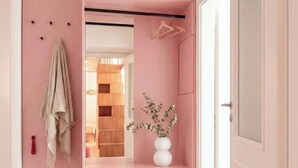 A pink-themed hallway with a bench, a door, and a mirror reflecting a wooden interior. - TurnKey | Wenceslas square Two-Level Apartment V (Praha 1)