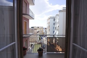 A balcony with a view of neighboring buildings and a potted plant.