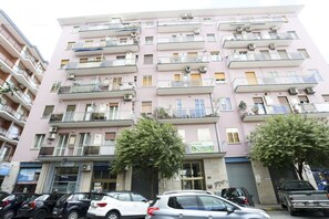 Un edificio residencial de varios pisos con balcones, unidades de aire acondicionado y una tienda en la planta baja.