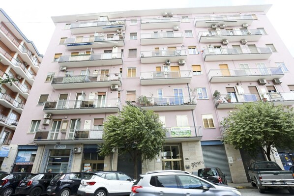 A multi-story residential building with balconies, air conditioning units, and a storefront at the ground level.