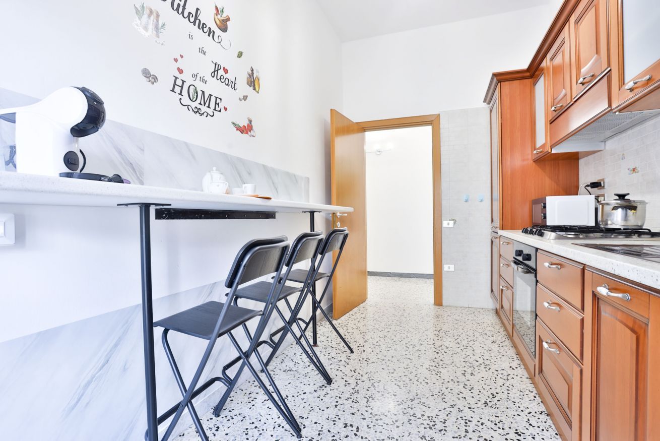 Une cuisine moderne dotée d’un plan de travail en marbre, de meubles en bois, d’un four encastré et d’une machine à café fixée au mur.
