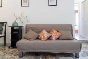 A neutral-toned sofa with patterned cushions, a black side table with a vase, and framed artwork on the wall. - Cozy 45 sqm apartment, able to accommodate up to 4 people, located on the first floor of a building with lift (some steps to access it) in the historic center of Syracuse. The accommodation is located on the island of Ortigia, right above the market, a f (Siracusa)