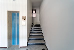 A staircase with a blue door and an elevator control panel.