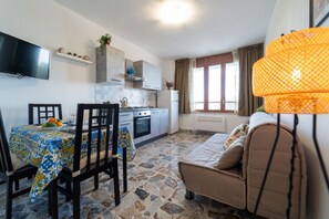 Un espace de vie compact comprenant un coin repas, une kitchenette et un canapé.