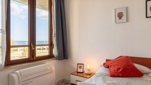 A bedroom with a bed, a nightstand, a picture frame, a radiator, and a window with curtains.