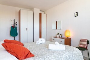 Une chambre à coucher avec un lit, des oreillers, une commode, une lampe, un miroir et une armoire.