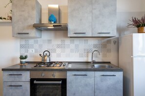 Une cuisine moderne avec des armoires grises, un évier en acier inoxydable et un pare-feu décoratif.