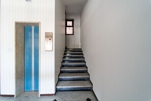 Un escalier avec une porte bleue et un panneau de commande d’ascenseur.
