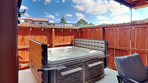 A hot tub with a stone exterior, a chair, and a wooden fence in the background.