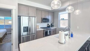 A modern kitchen with stainless steel appliances, a marble countertop, and pendant lighting.