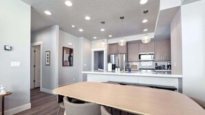 A modern kitchen with white countertops, stainless steel appliances, and recessed ceiling lighting.